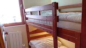 A bunk bed room with a radiator and a window.