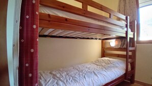 A bunk bed with a wooden frame and white bedding.