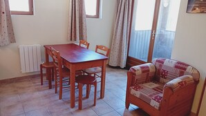 Un coin repas avec une table et des chaises en bois, un canapé à motifs et un radiateur.