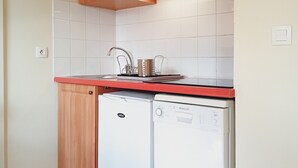A compact kitchen with wooden cabinets, a microwave, a dishwasher, and a tiled backsplash.
