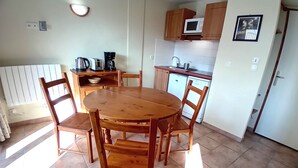 A compact kitchen with a round wooden table and chairs, a microwave, and a coffee maker.
