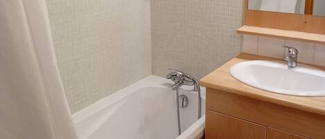 Un baño con bañera, ducha, lavamanos y un armario de madera.