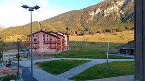A building with multiple balconies, a parking area, and a view of a mountainous landscape.