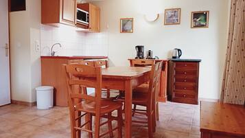 Une cuisine avec des meubles en bois, un four à micro-ondes, une machine à café et un évier. Deux tableaux encadrés sont accrochés au mur.