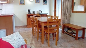 Cocina compacta con comedor, muebles de madera y una pequeña mesa con una cesta.
