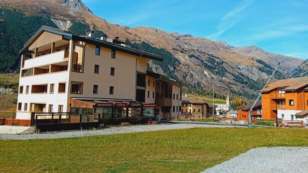 A multi-story building with balconies, a restaurant, and a view of mountains. - Terrasses D 305 - PARC NAT. VANOISE appart. 6 pers (Val Cenis)