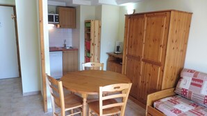 A compact kitchen with a dining table and chairs, a wooden cabinet, and a sofa. - Terrasses D 305 - PARC NAT. VANOISE appart. 6 pers (Val Cenis)