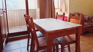 Un tavolo da pranzo in legno con sedie, una panca di legno e vista su un balcone con ringhiera in legno.