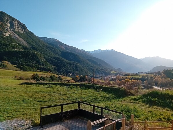 A scenic view of a mountainous landscape with a wooden deck and a clear sky.