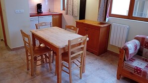 A compact kitchen with a wooden table and chairs, a small countertop, and a radiator near a window.