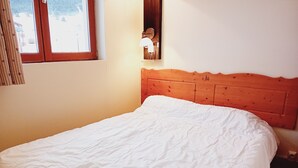A bedroom with a wooden headboard, a white bedspread, and a window with curtains.