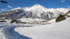 Ein mit Schnee bedeckter Berg mit einer Seilbahn und einem kleinen Dorf im Tal.