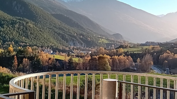 Eine Berglandschaft mit Blick auf ein Tal und ein Gebäude in der Ferne.