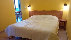 Ein Bett mit Holz Kopfteil, ein Nachttisch und ein Stuhl in einem Raum mit gelben Wänden.
