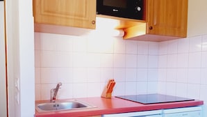 Eine Küche mit Holzausstattung, einer Mikrowelle, einem Spülbecken und einem Geschirrspüler.