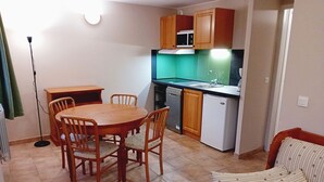 A compact kitchen with a dining table and chairs, a microwave, a dishwasher, and a small refrigerator. - Terrasses D 309 - PARC NAT. VANOISE studio 4 pers (Val Cenis)