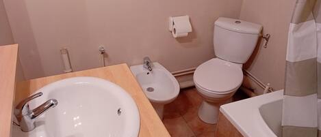 Un baño con lavamanos, bidé, inodoro y bañera.