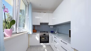 Eine moderne Küche mit weißen Schränken, einem Einbauofen und einem Fenster mit einem Blumentopf.