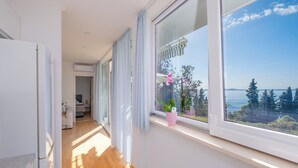 Ein heller Raum mit großem Fenster, Holzboden und einem Blumentopf auf der Fensterbank.