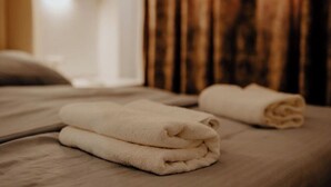 Ein ordentlich bezogenes Bett mit zwei gefalteten weißen Handtüchern.
