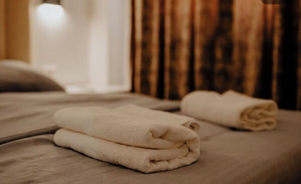 A neatly made bed with two folded white towels. - Suite Dolce Vita (Tirana)