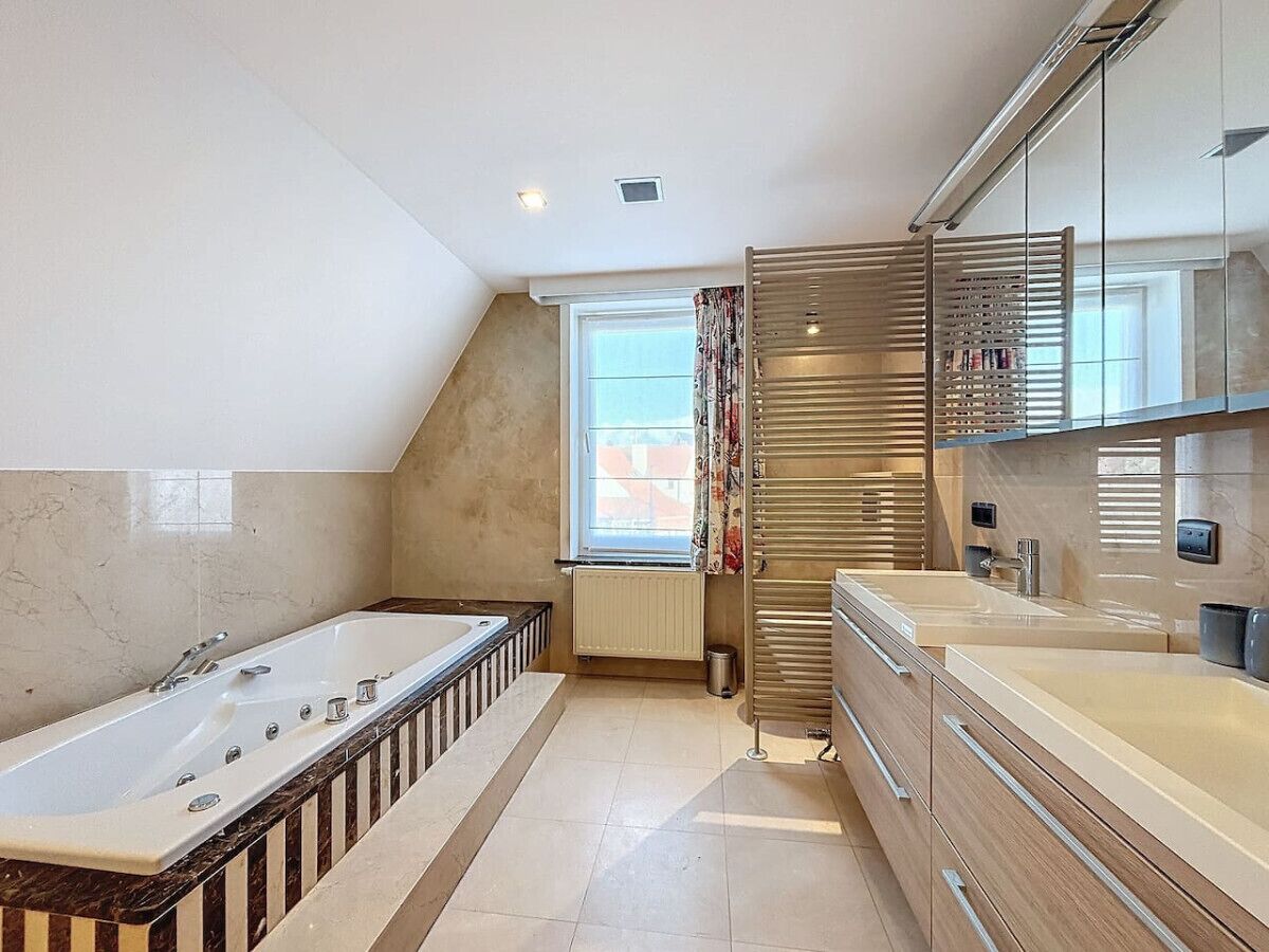 Ein modernes Badezimmer mit einer großen Badewanne, einer Dusche und einem Waschtisch mit Spiegel.