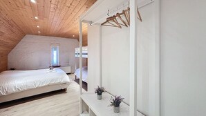 Una camera da letto con soffitto in legno, un letto, un armadio e una piccola finestra.