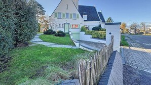 Una casa residenziale con un prato curato, una recinzione in legno e un cielo sereno.