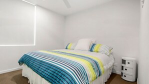 A bedroom with a bed, white walls, a window, and a bedside table with drawers. - Aquaview Unit 604, 29 Canberra Tce, Kings Beach (Kings Beach)