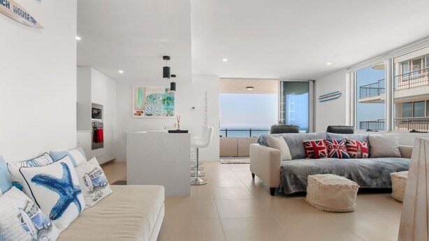 A modern living room with a sofa, ottoman, and a view of the sea. - Aquaview Unit 604, 29 Canberra Tce, Kings Beach (Kings Beach)