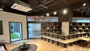 Een modern interieur met een receptiebalie, zithoek en planken met decoratieve items.