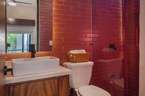 A bathroom with a white sink, wooden cabinets, a white toilet, and a red-tiled shower area. - Suite Tropical N11 Downtown (Cozumel)