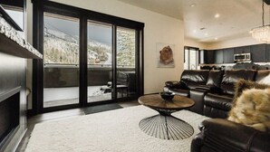 A modern living room with a fireplace, a dining area, and a kitchen.
