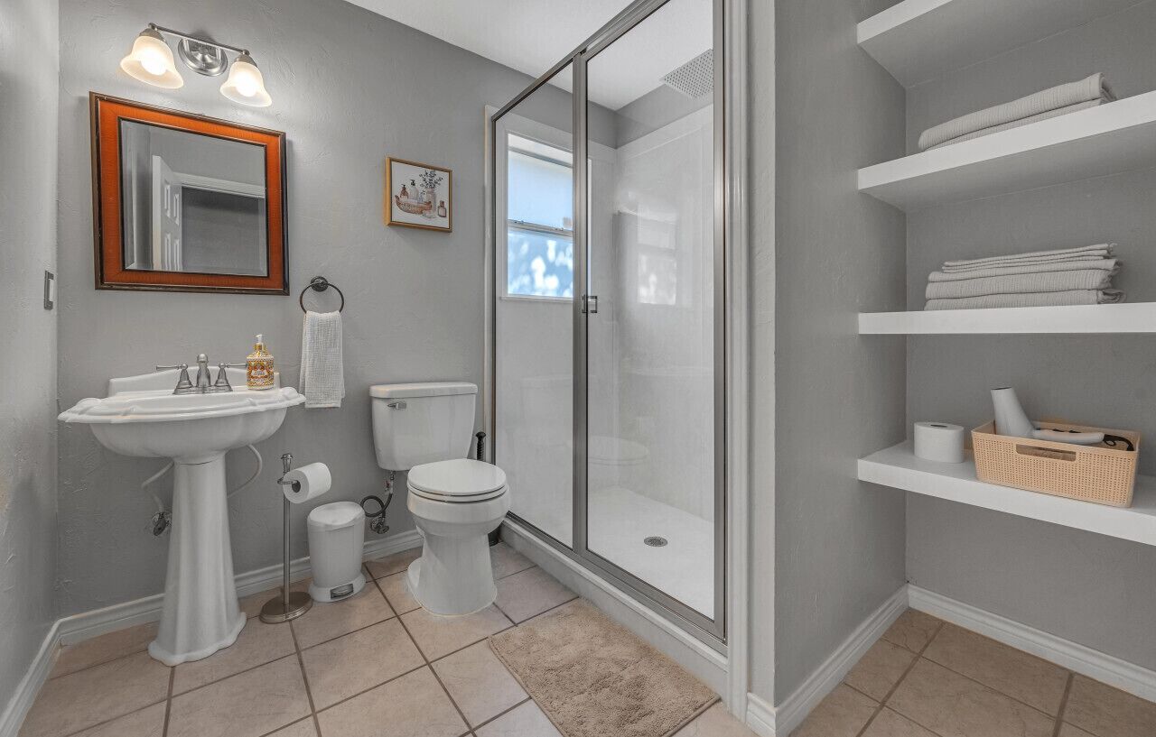 Ein Badezimmer mit einem Standwaschbecken, einer Toilette und einer Duschkabine aus Glas.