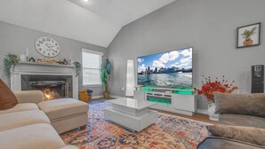 Ein Wohnzimmer mit Kamin, großem Flachbildfernseher und Blick auf die Stadt.