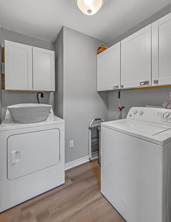 A laundry area with two white washing machines, a dryer, and a small cart.