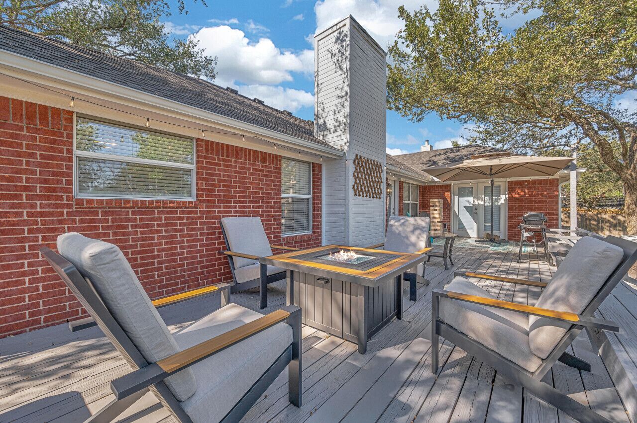 A patio with a fire pit, outdoor seating, and a brick building with large windows.