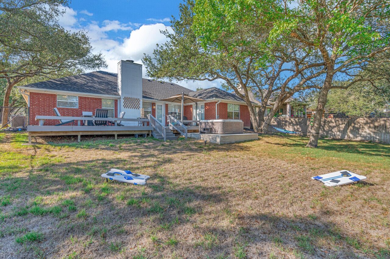 A two-story house with a covered patio, a chimney, and a fenced yard.