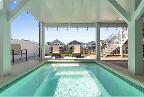 Zona de piscina con vista a edificios residenciales, un área de estar techada y una escalera.
