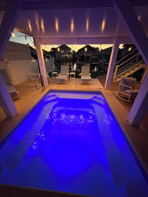 A hot tub with a blue light, surrounded by lounge chairs and a covered patio area. - Canal Front-Private Pool!Dock,Tiki Bar,Putting Green⛳️ Steps to the Beach! (Ocean Isle Beach)