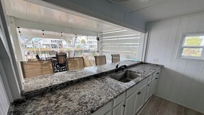 A kitchen with a granite countertop, stainless steel sink, and white cabinetry. - Carolina Tide!5⭐️ Canal Front-Private Pool!Dock,Tiki Bar and Steps to the Beach! (Ocean Isle Beach)
