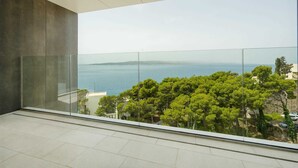 A modern interior with a large glass balcony overlooking a coastal landscape. - Luxury Villa Beyond Waves with Pool (Baška Voda)
