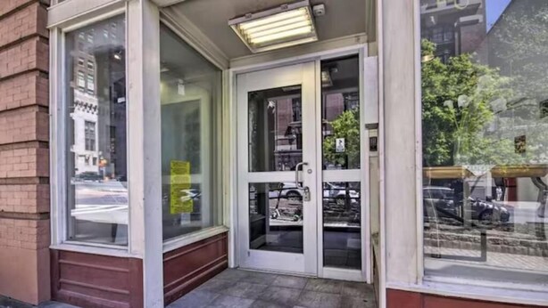 Een gevel met glazen deuren, een klein portiek en een straatbeeld zichtbaar door de ramen.