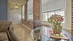 Een moderne woonkamer met een glazen tafel, een leren bank en een bakstenen muur.