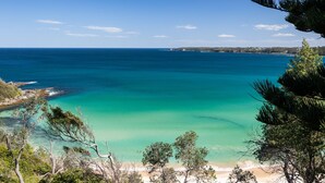 A coastal landscape with clear turquoise waters, sandy beach, and dense greenery. - Oceans Edge - Spectacular home with ocean views on the hill of Mollymook Beach (Mollymook Beach)