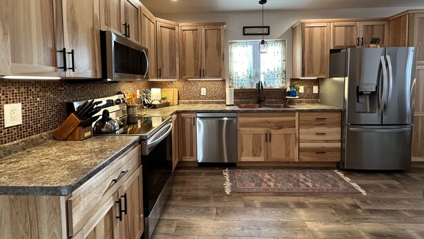 Une cuisine moderne avec des meubles en bois, des appareils en acier inoxydable et un dosseret carrelé.