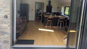 A modern kitchen with a central island, wooden stools, and a dining area with a sofa and a coffee table. - The Barn @ Tyn y Ffridd , great views,
 WiFi, log burner (Denbighshire)