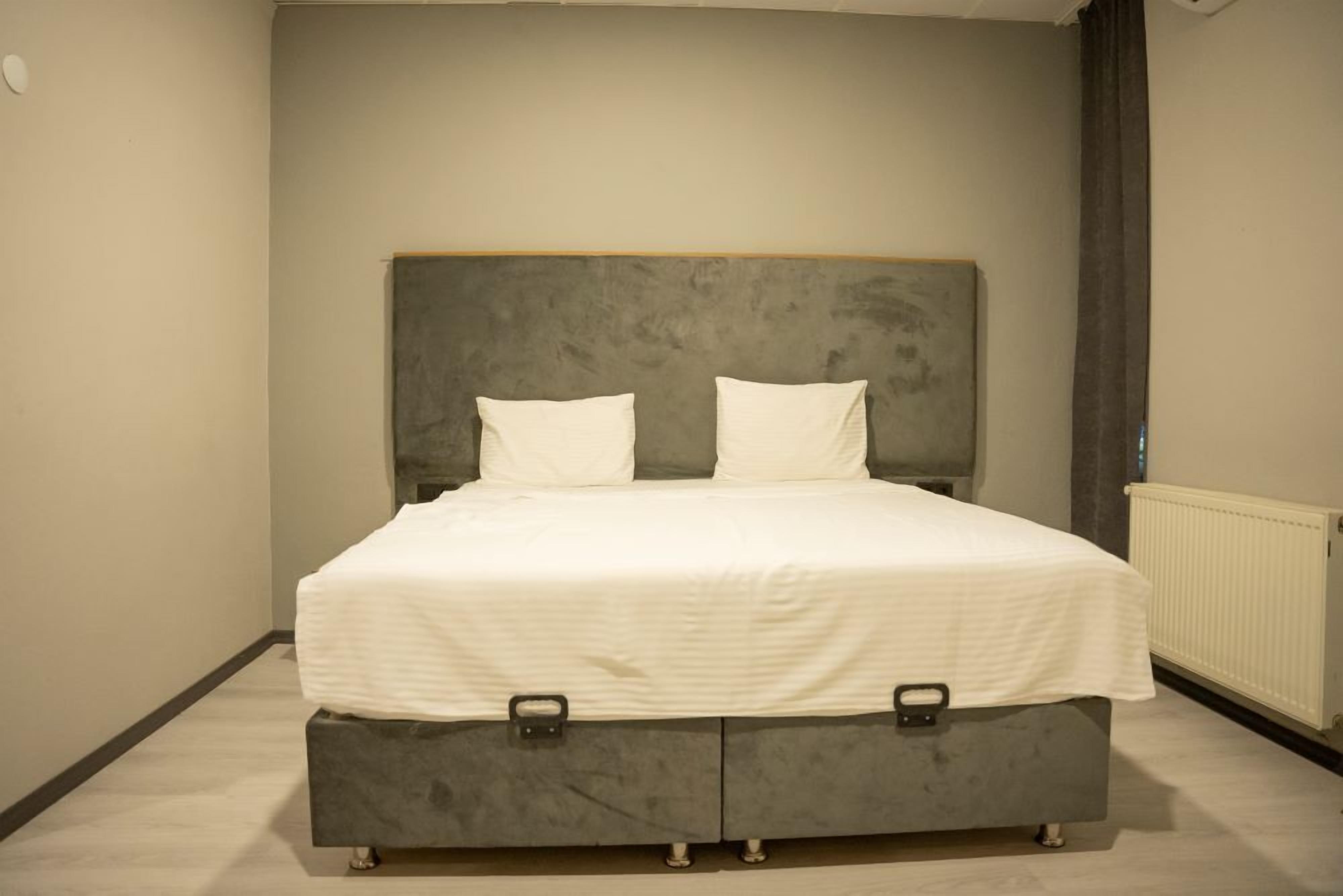 Un dormitorio con una cama, dos almohadas y un cabecero gris.