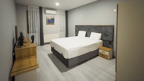 A modern hotel room with a large bed, a wooden desk, a nightstand, and a window with curtains. - Altınova Hotel Sakarya  (Serdivan)