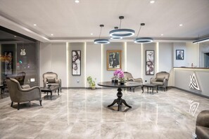 A modern lobby with a marble floor, leather armchairs, a round table with a vase, and pendant lighting. - Altınova Hotel Sakarya  (Serdivan)
